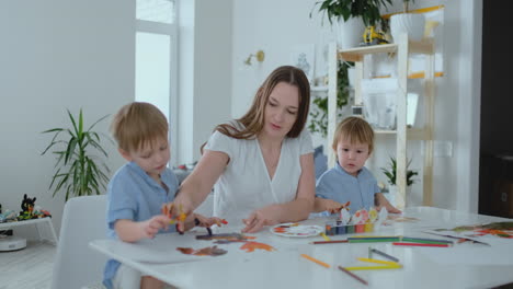 two children of boys and mother are engaged in creative development doing homework by fingering on paper. the development of tactile sensations and small mathematics.