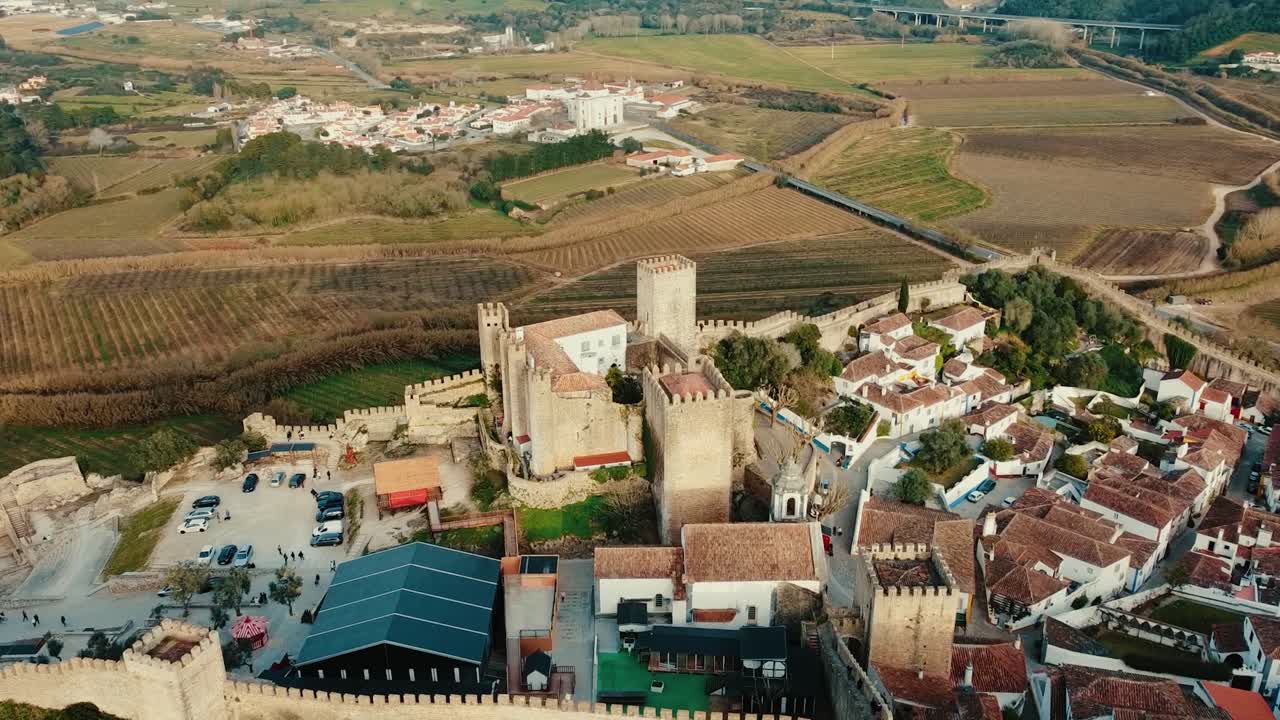Ripresa aerea cinematografica della Torre D. Fernando a Óbidos, in orbita e in volo sopra la torre medievale e la città fortificata circostante, che mette in mostra l'architettura storica per viaggi e patrimonio culturale
