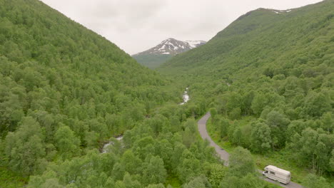 campervan navigating on mountain pass in the valley of erdal with river flowing through trees in norway