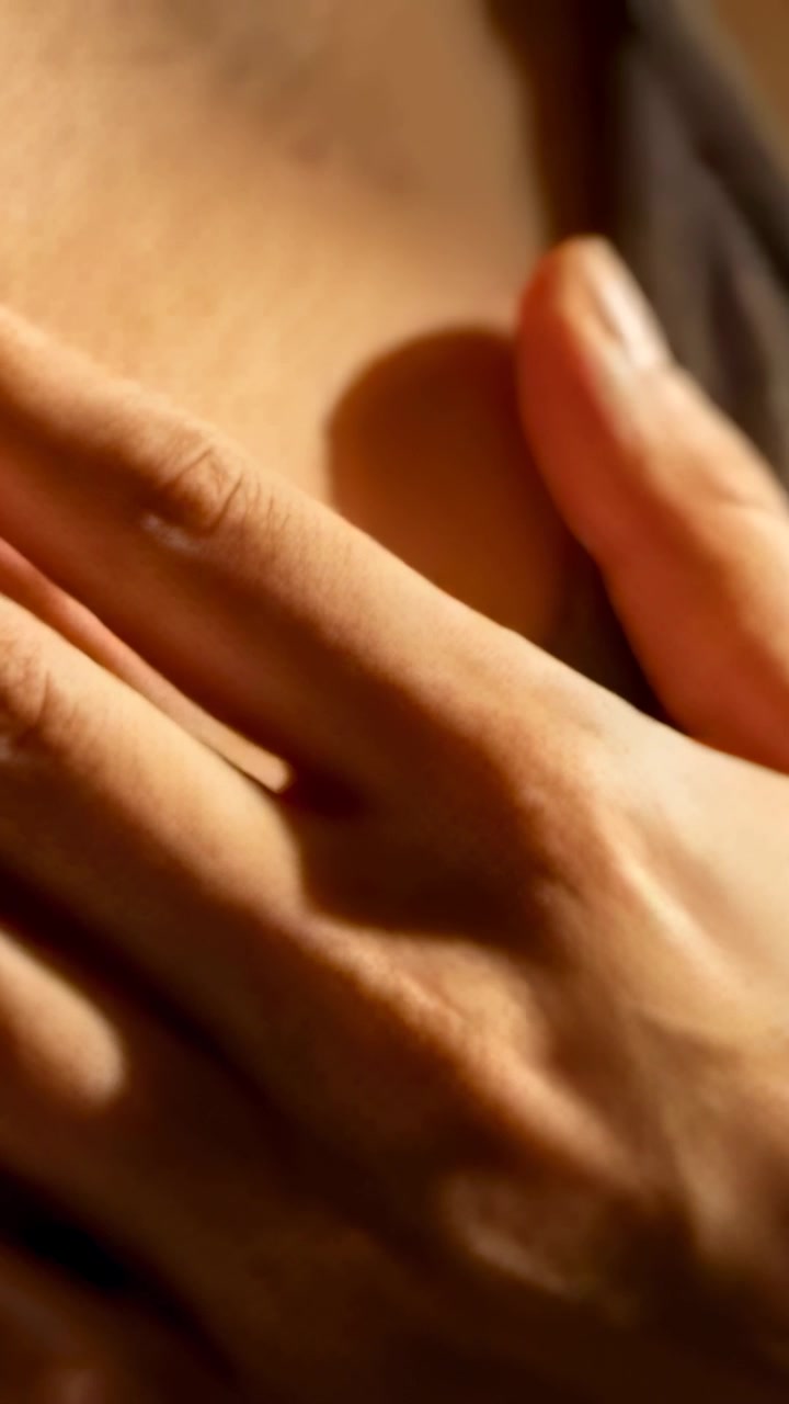 Vertical video: Closeup starting, hand resting and shifting on shoulder in bed showing strap