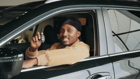 man smiling holding car keys in new car