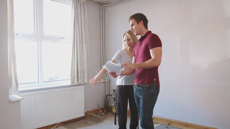 couple buying house for first time looking at house survey in room to be renovated