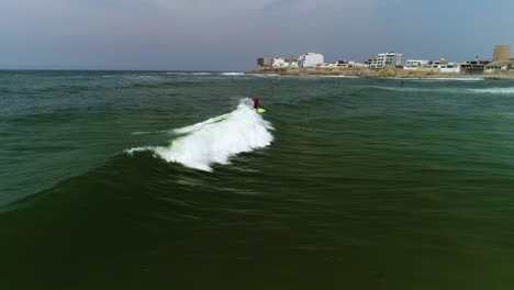 Aerial-view-of-a-man-crashing-in-a-wave-while-surfing-in-sunny-San-Bartolo,-Peru