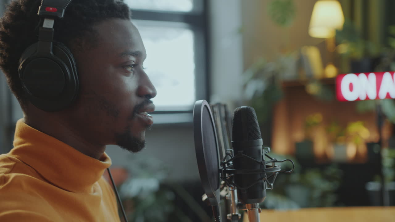 Joyous Black Man in Headphones Recording Podcast Interview in Studio