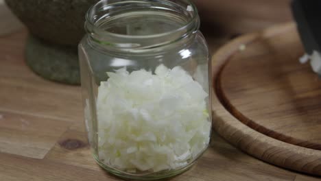 adding chopped onion to a glass jar, close up