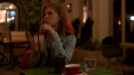 woman enjoying lemonade at a night cafe