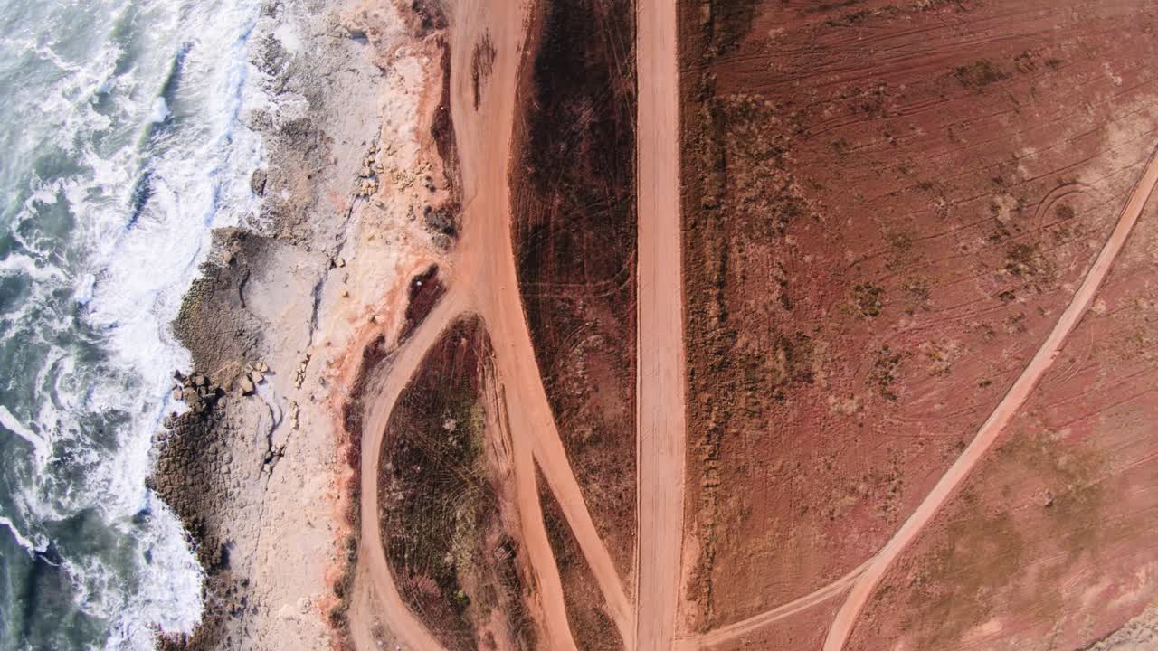 tiro de seguimiento de vista de pájaro de la costa desde arriba de caminos de tierra, soleado, 4k 60fps