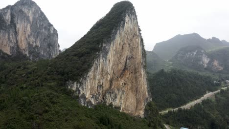 Dramatic-karst-mountain-rock-face-in-mountainous-China-valley,-aerial-view