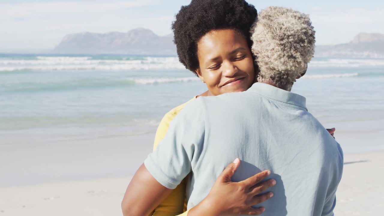 Happy african american couple dancing and embracing on sunny beach