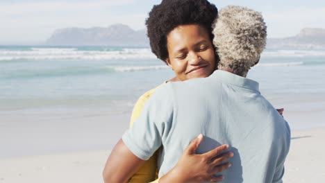 gelukkige afro-amerikaanse echtpaar dansen en omhelzen op een zonnig strand