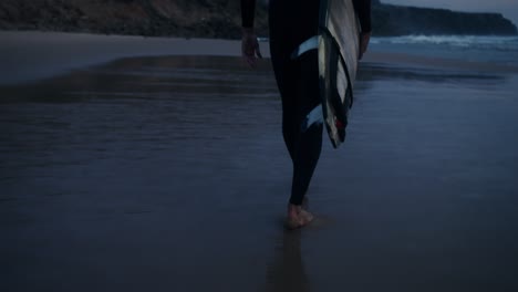 surfista caminando por la playa al atardecer