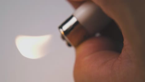 person shakes plastic lit lighter in white background macro