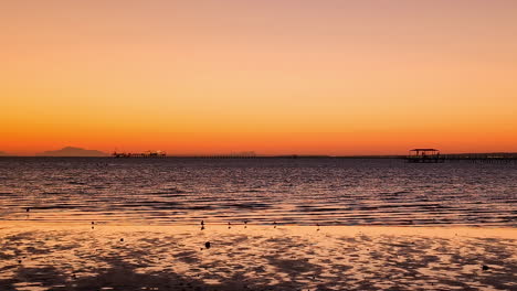 Schwenkaufnahme-Eines-Atemberaubenden-Orangefarbenen-Himmels-Nach-Sonnenuntergang-Am-Späten-Abendhimmel-Von-Einem-Sandstrand