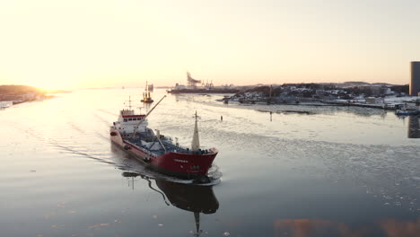 drone circulating a large fishing boat near the harbor of gothenburg, sweden during sunset in the cold winter time