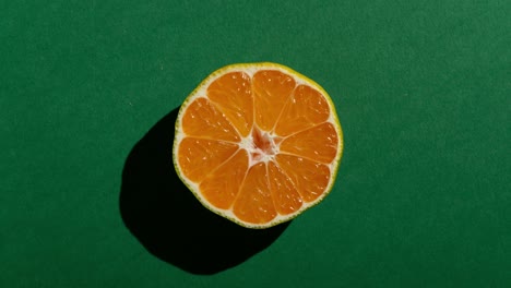 medias frescas de mandarina con una fuerte sombra en fondo verde. animación de movimiento de parada