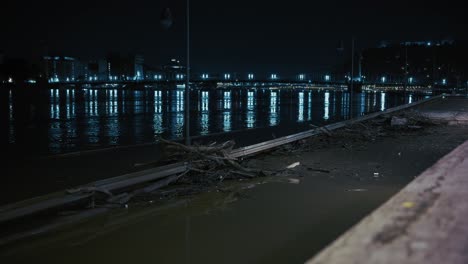 night view of budapest's flooded streets, debris and damaged guardrails along the riverbank