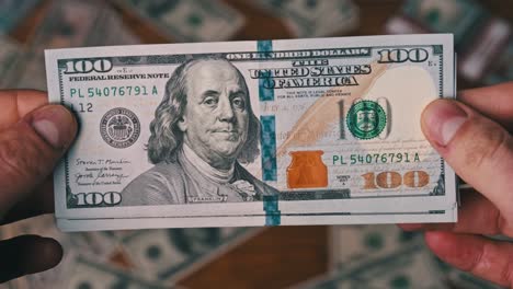 dollars in male hands on background of table with money, counting banknotes