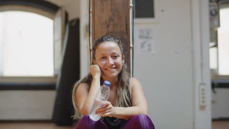 vista frontal de la profesora de danza sentada en el suelo en el estudio y mirando al frente