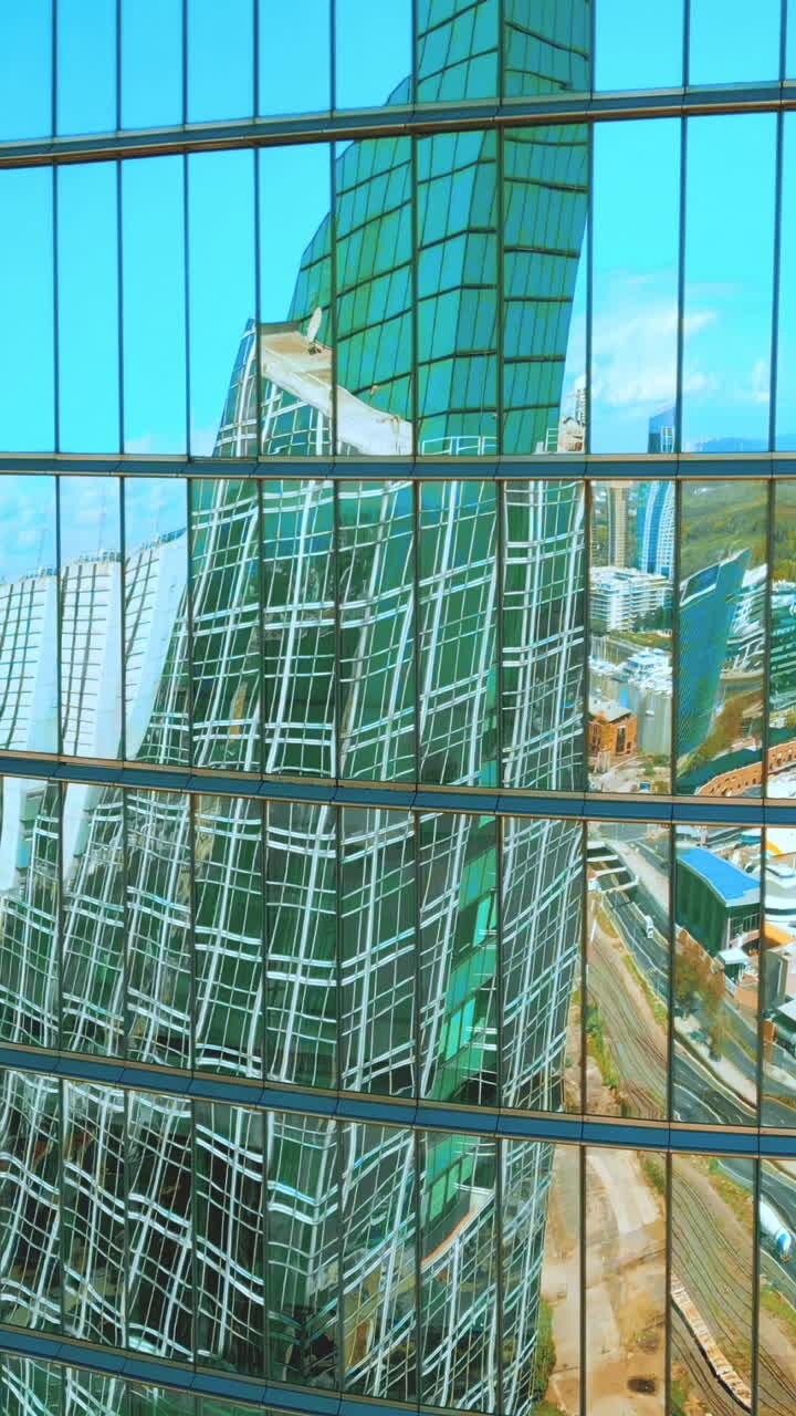 Fachada moderna de edificio de cristal que refleja el paisaje urbano