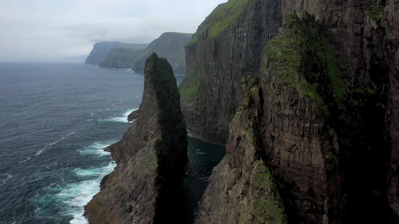 Aerial flight along rugged Faroe Islands coastline through clifftops, drone