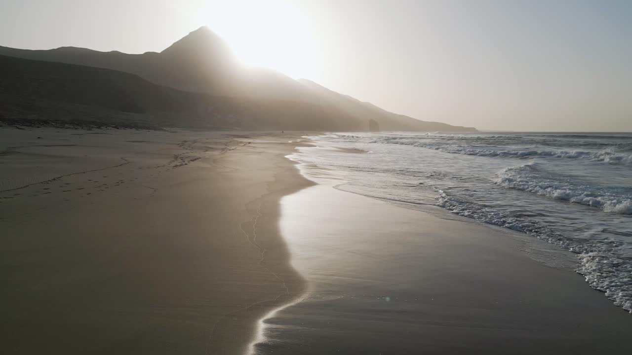 Aerial drone shot of Cofete Beach in Fuerteventura, showing vast sand, deep blue ocean, and the untouched Atlantic coastline.