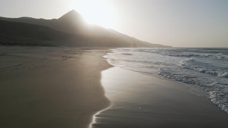 aerial drone shot of cofete beach in fuerteventura, showing vast sand, deep blue ocean, and the untouched atlantic coastline.
