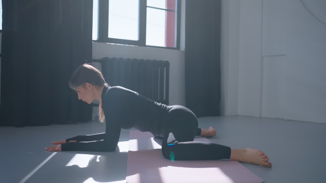 mujer haciendo una postura de yoga en una alfombra en un estudio