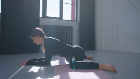 woman doing a yoga pose on a mat in a studio