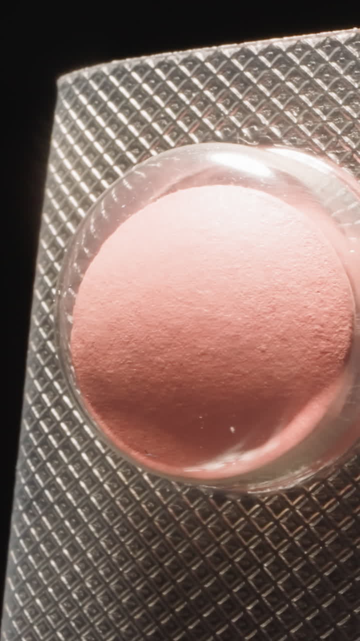 Curved silver blister texture with pink pills under transparent shell on black background. Effective and strong painkillers prescribed by doctor macro