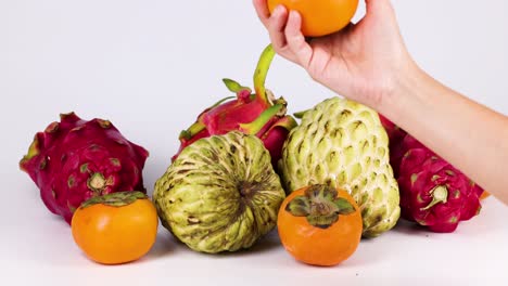 a hand selects fruit from a colorful arrangement