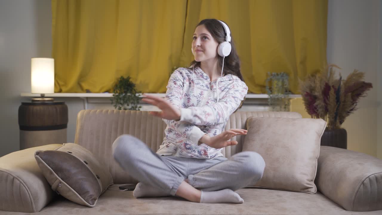 Young woman dancing at night while listening to music at home.