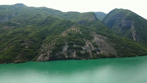 albania, lake koman amidst the accursed mountains, a boat sailing on emerald waters