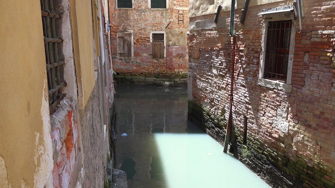 Canale stretto tra vecchi edifici in mattoni a Venezia.