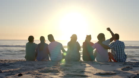 diverse group of friends enjoy a serene beach sunset, with copy space