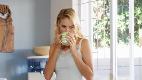 una mujer rubia bebiendo una taza de café.