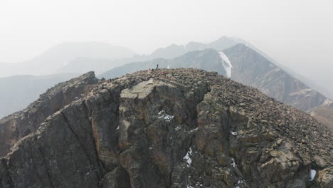 Climbers-On-Summit-of-Rocky-Mountain-Cliffs---Aerial-4K