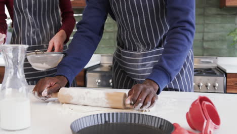 Happy-diverse-couple-standing-in-kitchen-and-rolling-dough,slow-motion