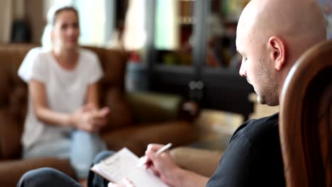 A therapist takes notes during a counseling session with a client