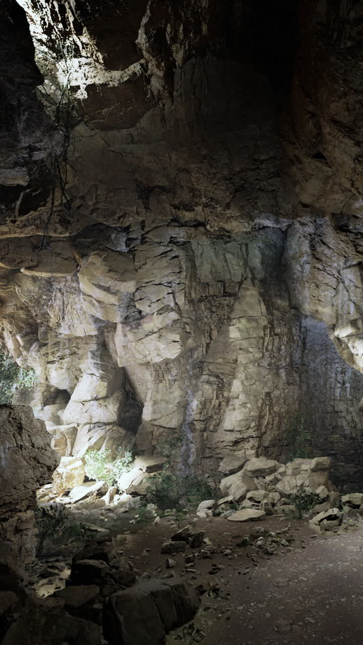 Esplorazione di una grotta con pareti rocciose e vegetazione rada in un ambiente naturale