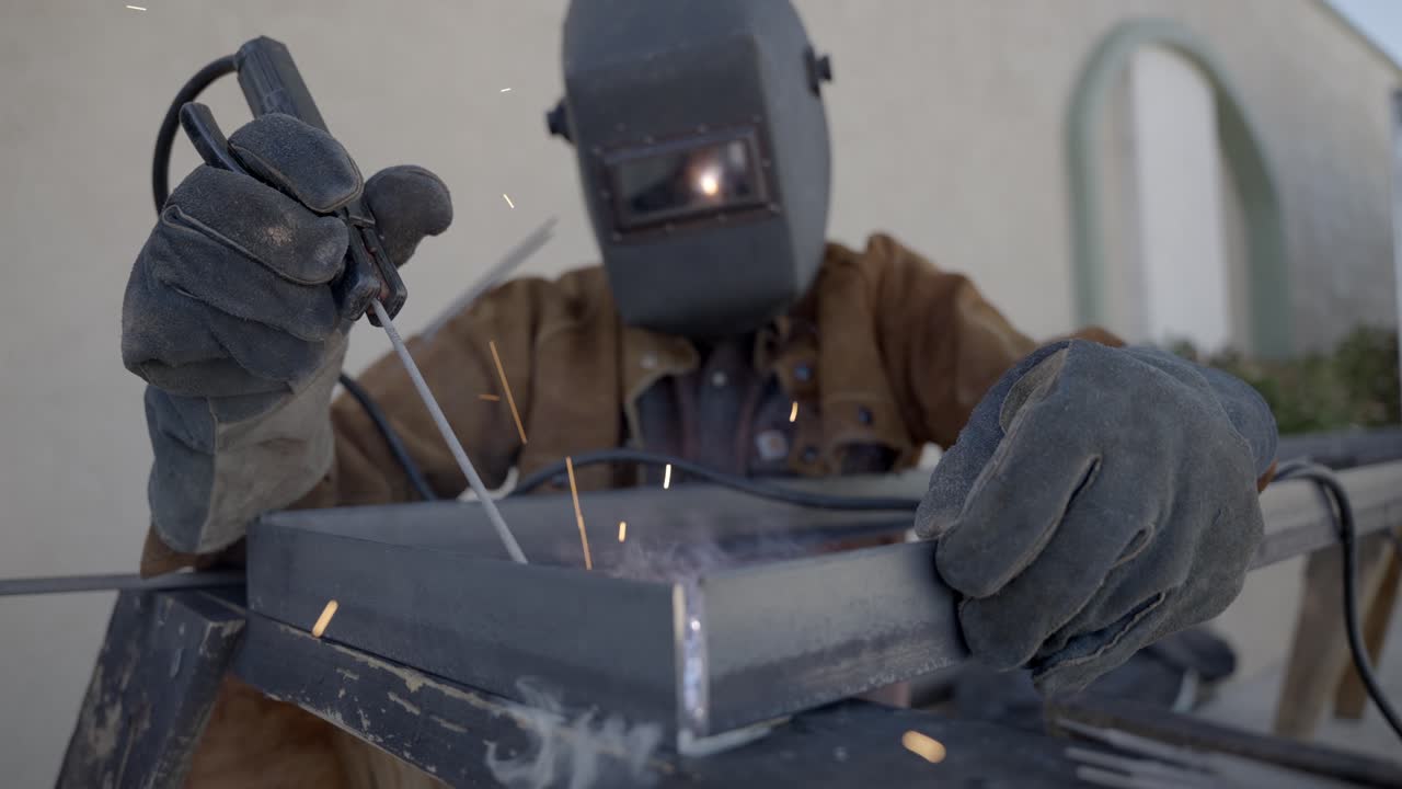 Front shot of welder working on welding a metal object, protective equipment