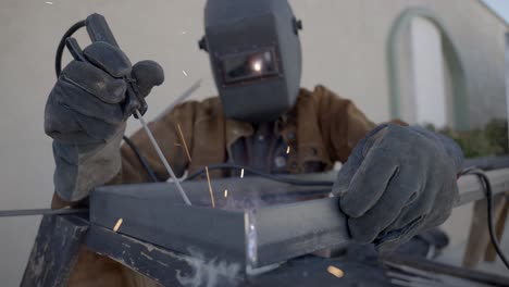 front shot of welder working on welding a metal object, protective equipment