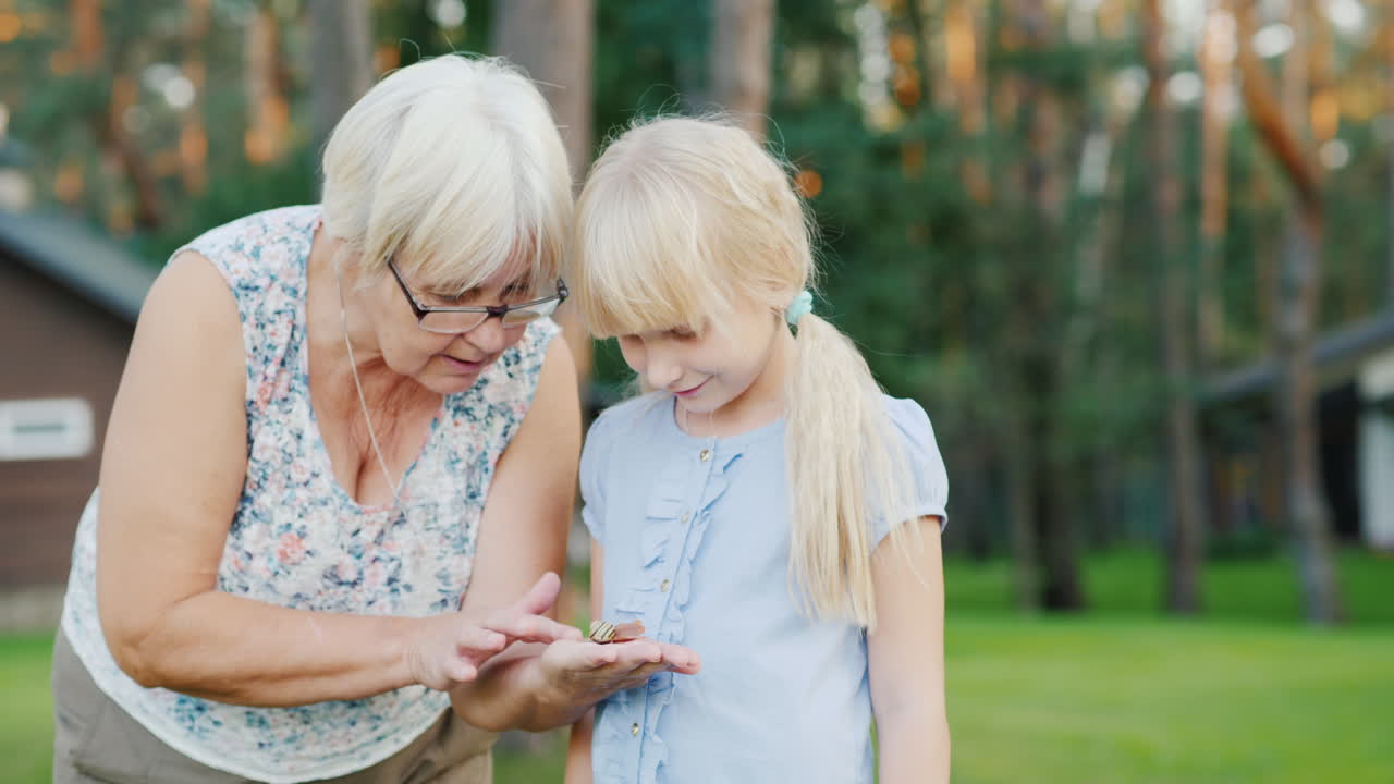 6세 소녀는 손에 있는 작은 달팽이를 본다 - 자연과의 소통