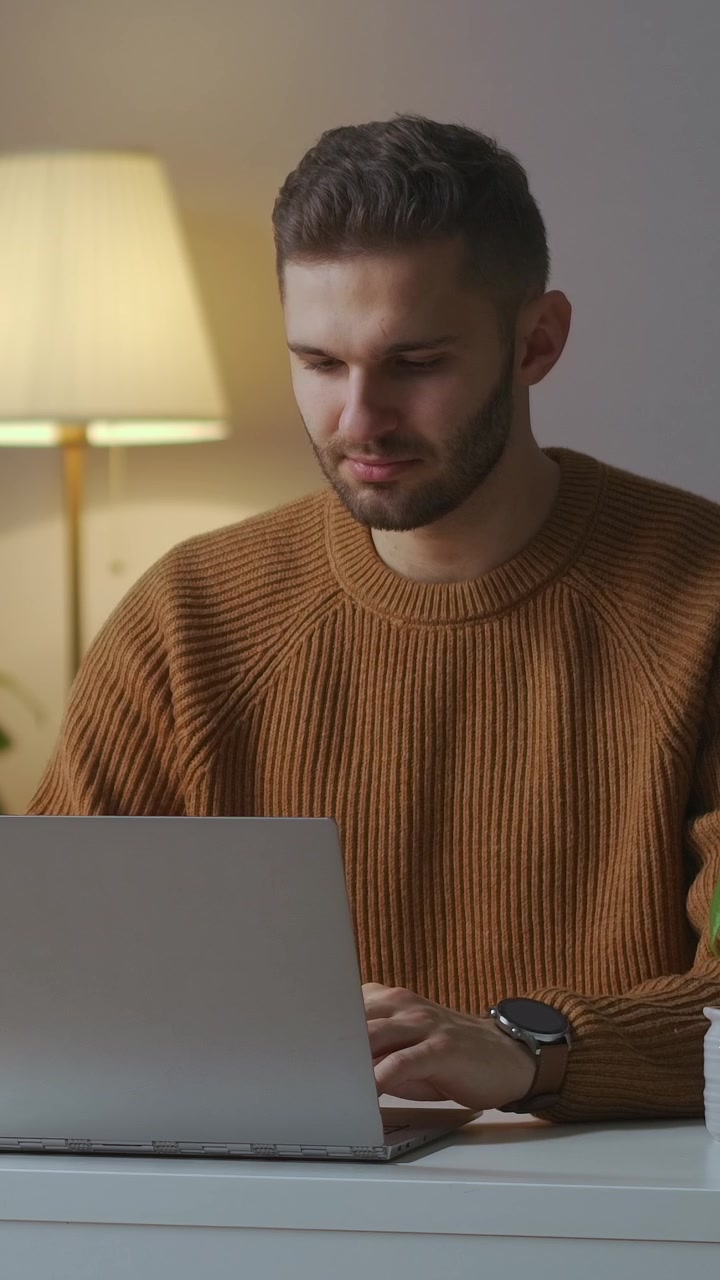 Focused Young Man Typing on Laptop in Home Office