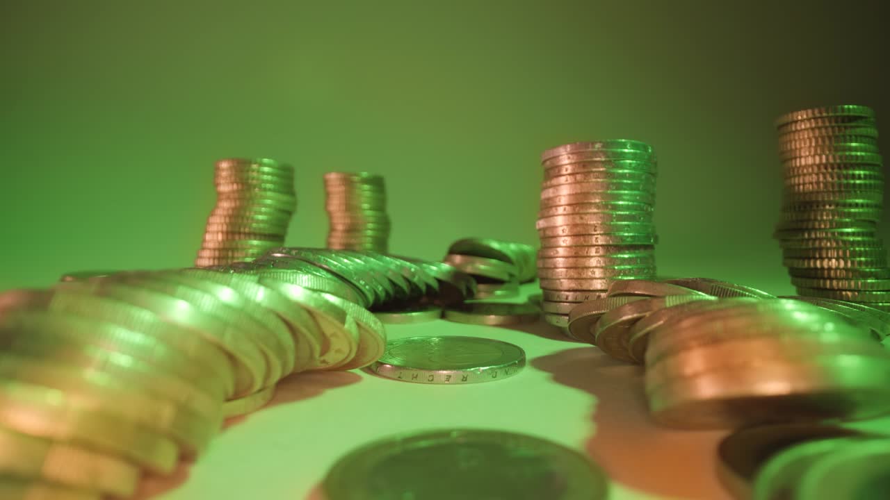 pilas de monedas caen sobre la mesa a la luz verde suave