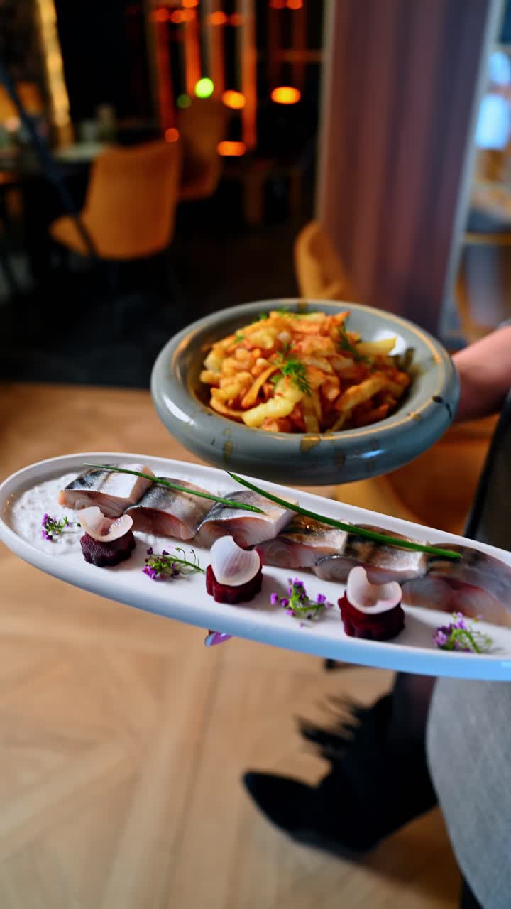 Sliced cured fish appetizers with beet garnish on white platter. Sliced fish arranged on white sauce with beet slices and microgreens on a long ceramic plate in a restaurant