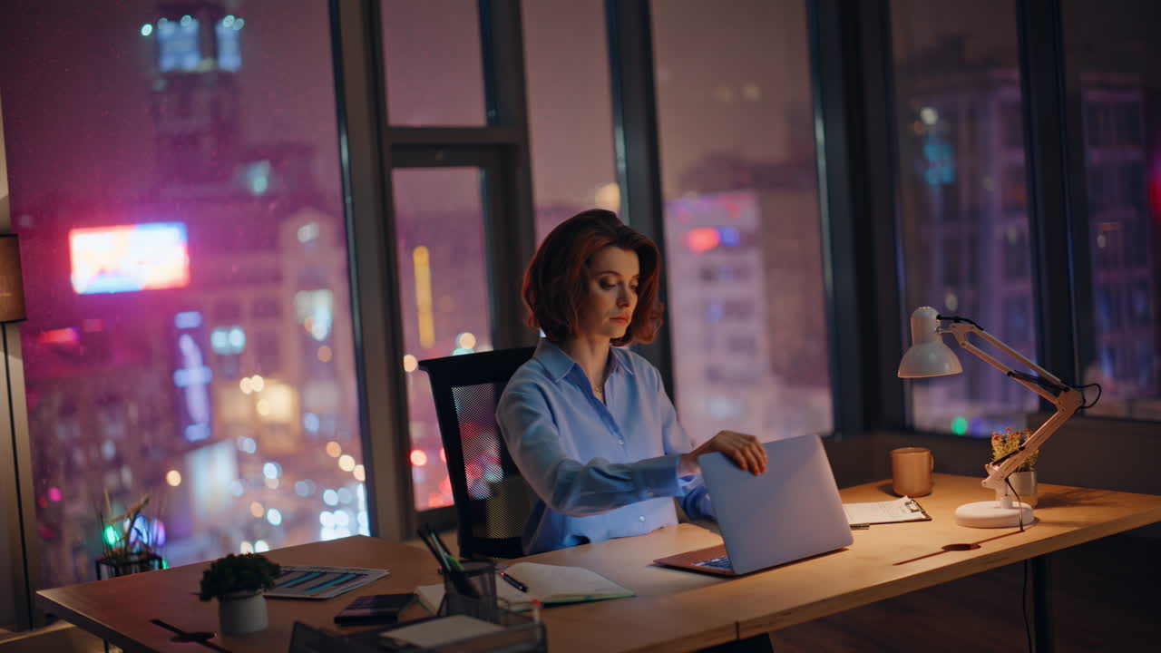 Dipendente demotivato seduto di notte sul posto di lavoro con sensazione di burnout. Donna stanca