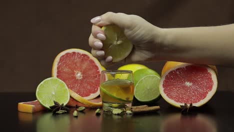 mujer exprime jugo de limón en una taza de vidrio con cóctel de alcohol