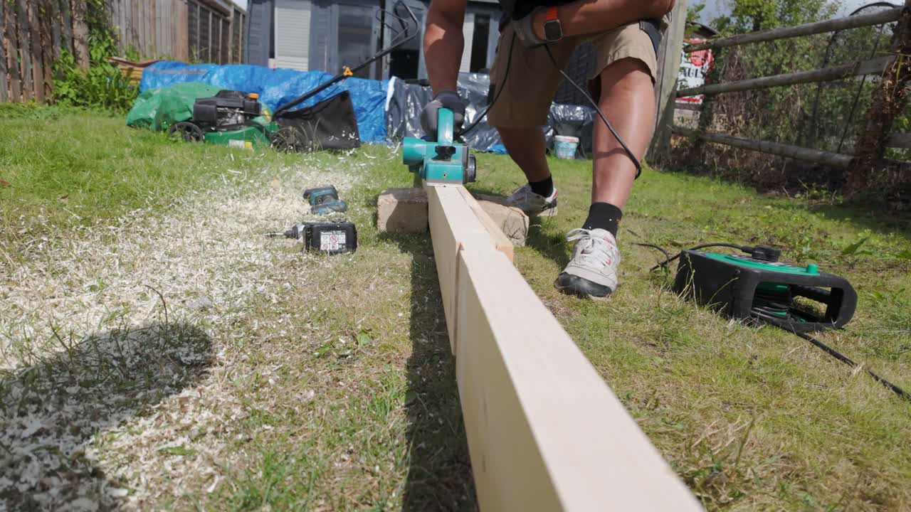 Campo lungo, carrellata in avanti, su una pialla utilizzata su una tavola in giardino in una giornata di sole.