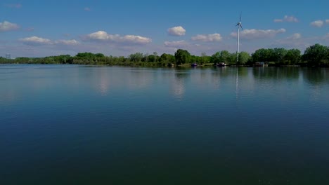 Drone-Sobre-El-Danubio-Cerca-De-Viena-En-Austria-Vuelo-Hacia-La-Isla-Del-Danubio-Con-Vistas-A-Un-Bosque-Y-Una-Turbina-Eólica