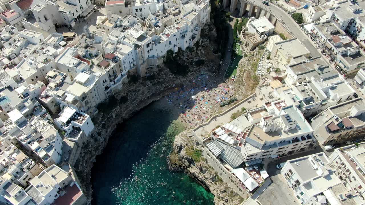 drone se acerca a la playa de polignano a mare en italia y se puede ver el agua azul cristalina del mar adriático